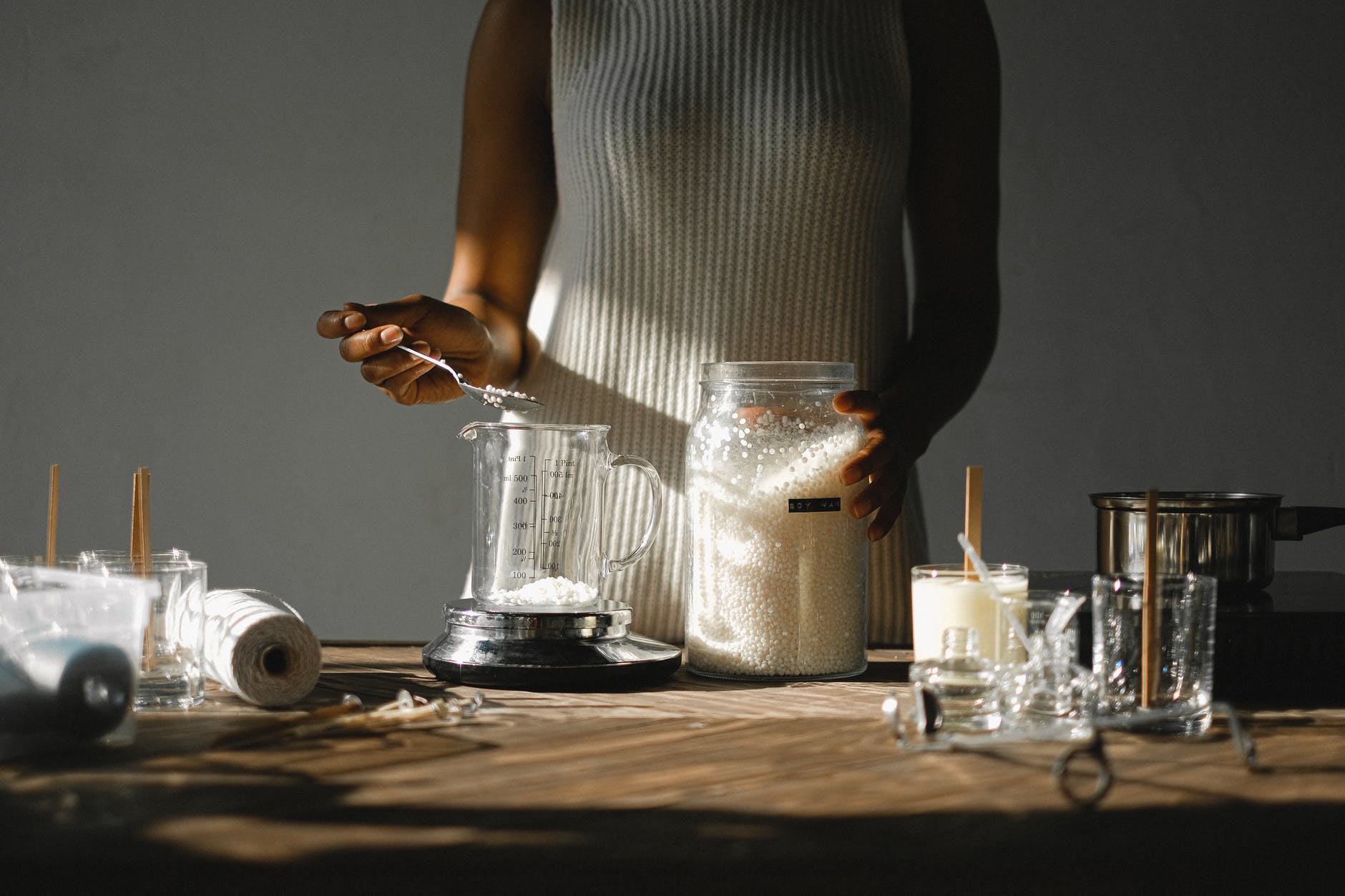crop black woman pouring wax into beaker